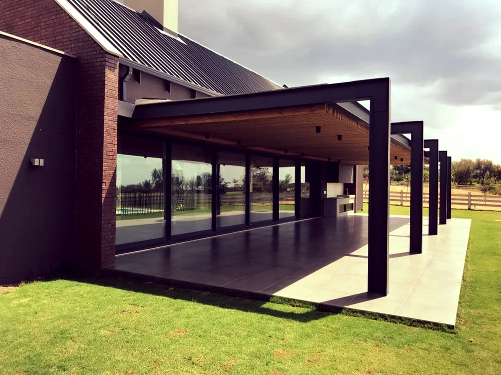 Amoretti timber and steel entertainment area with sliding glass doors overlooking a pool