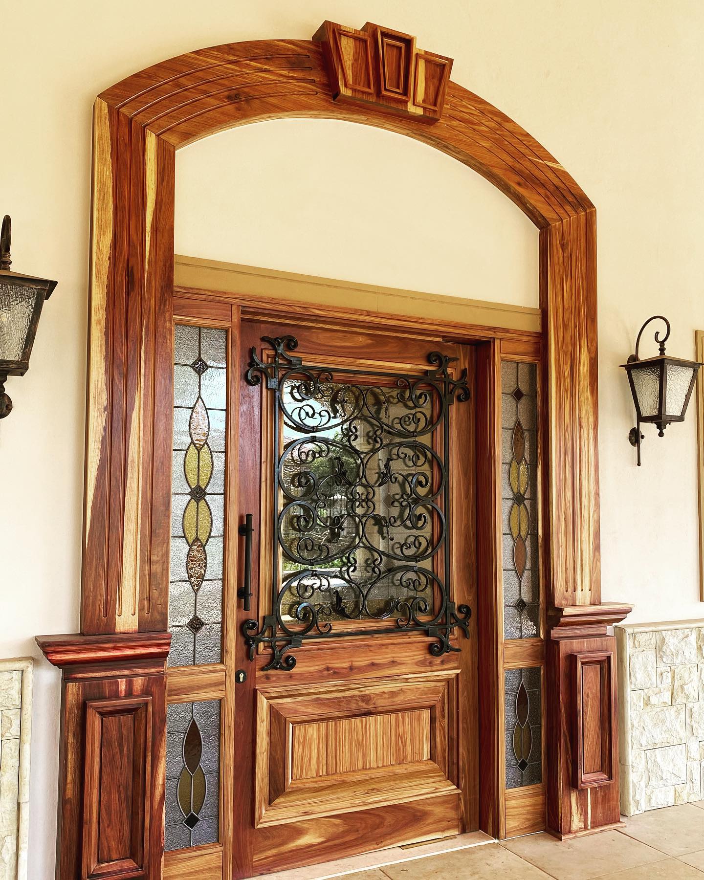 Ornate arched timber doorway with wrought iron scrollwork and stained glass sidelights