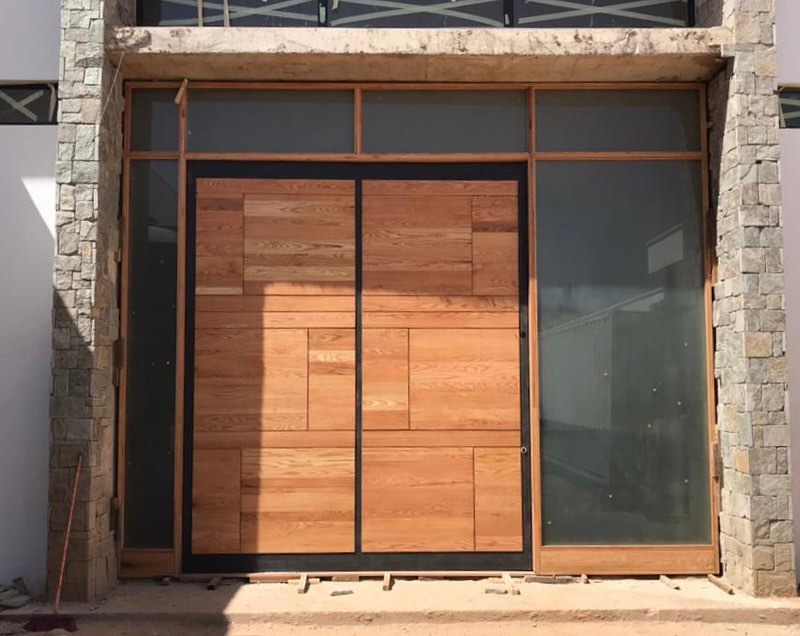 Modern block-panel double door in a stone surround with steel framing and sidelights