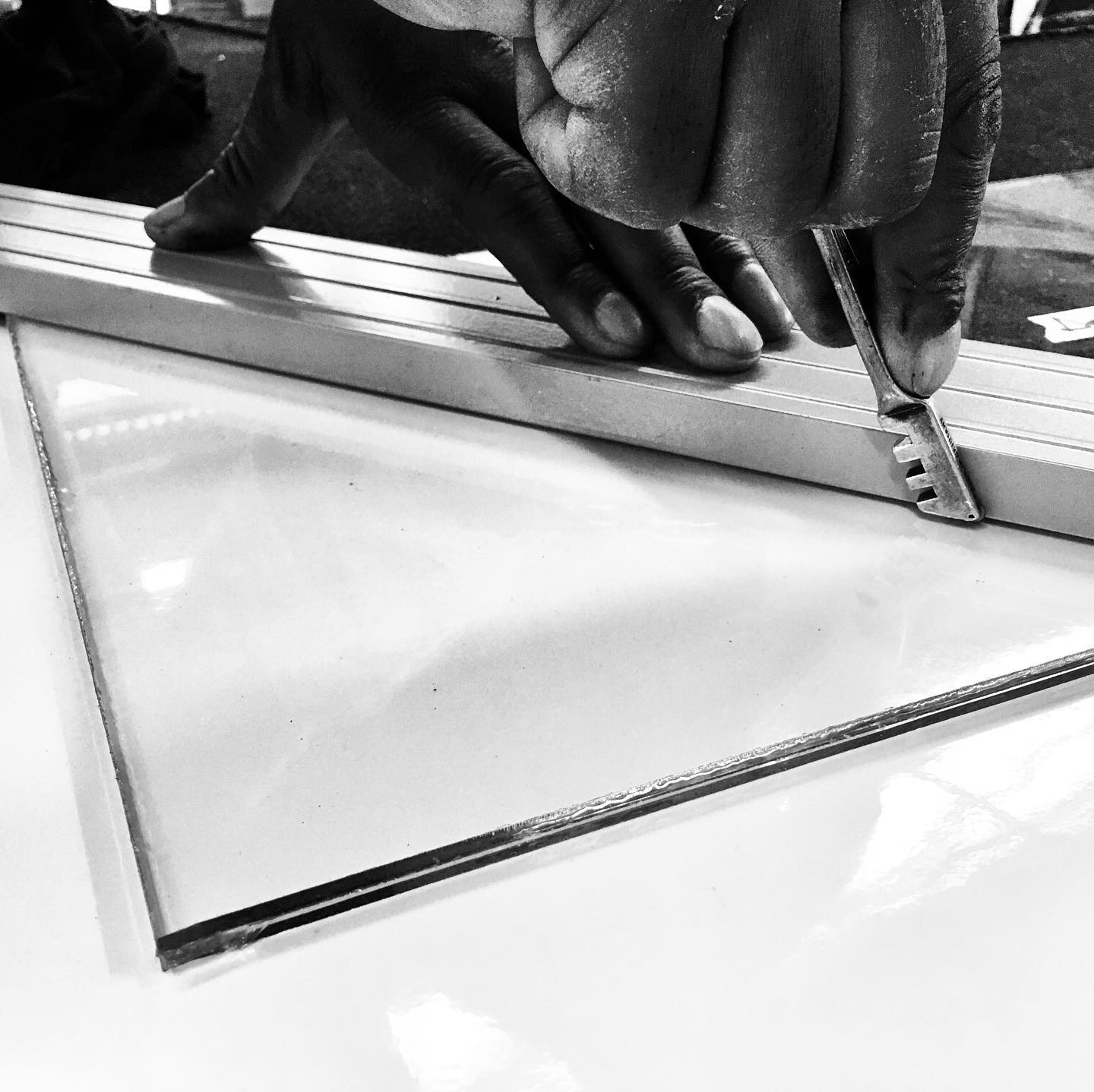 Black and white close-up of hands fitting a glass pane during installation