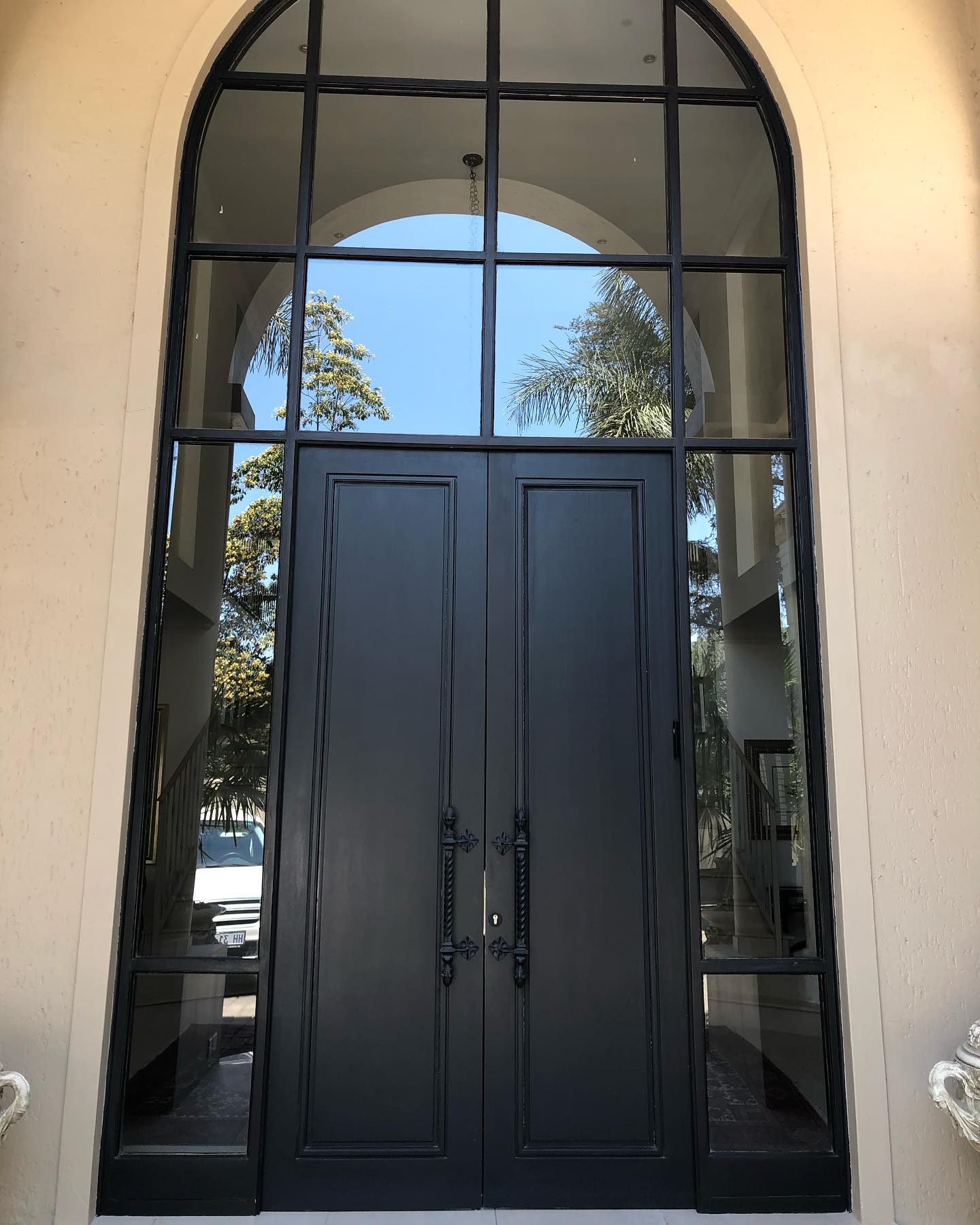 Arched black double door with a glazed fanlight and sidelights