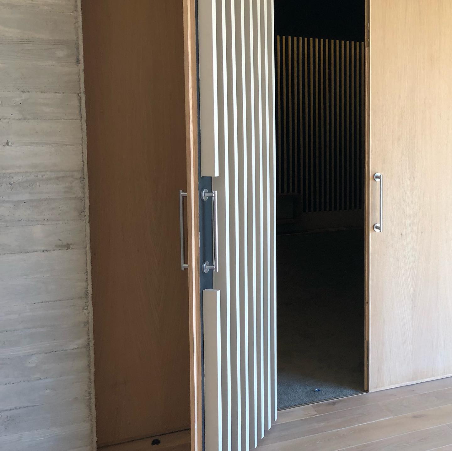 Fluted sliding timber door beside a flush oak door in an interior corridor