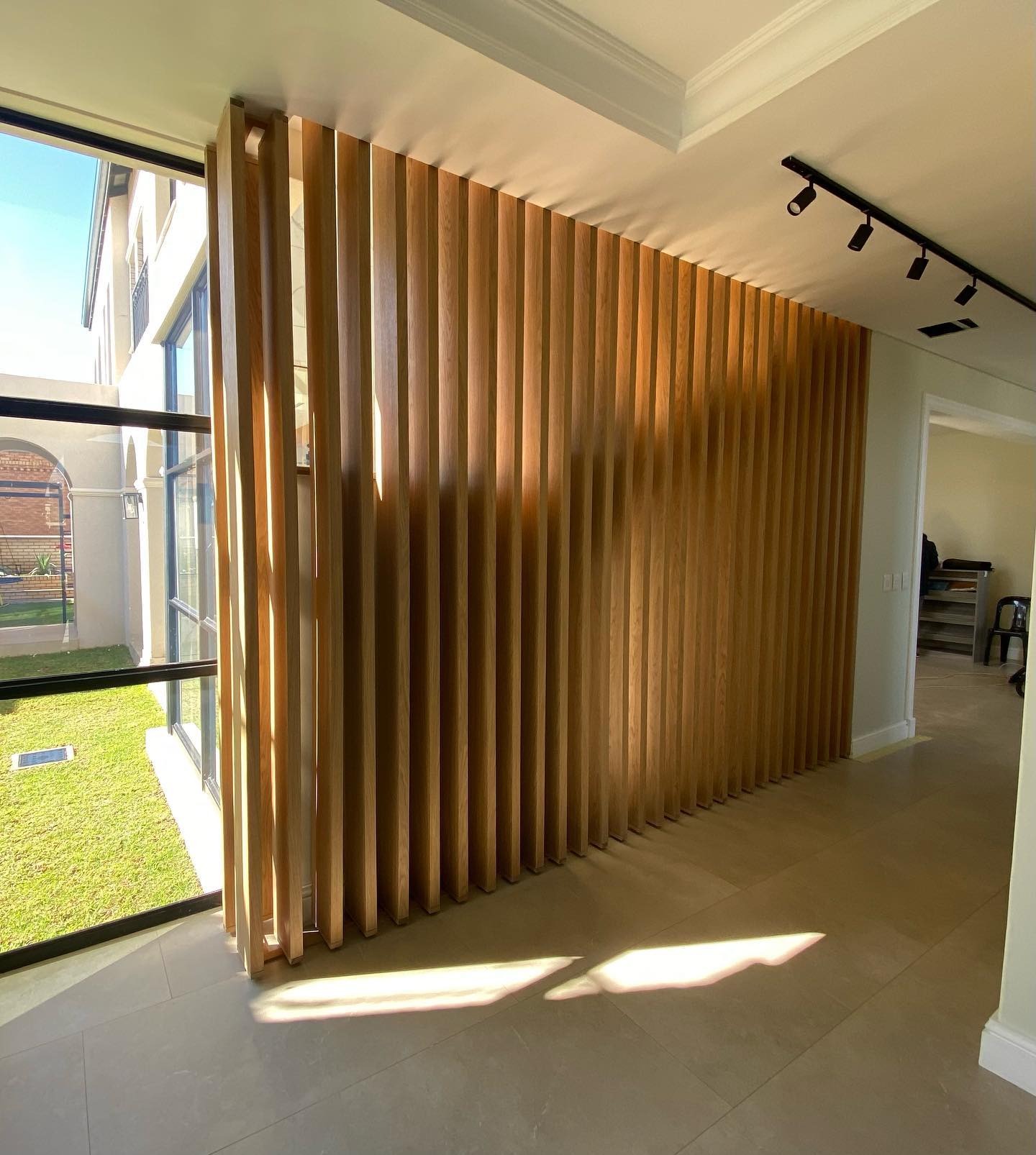 Vertical oak slat room divider in a sunlit interior