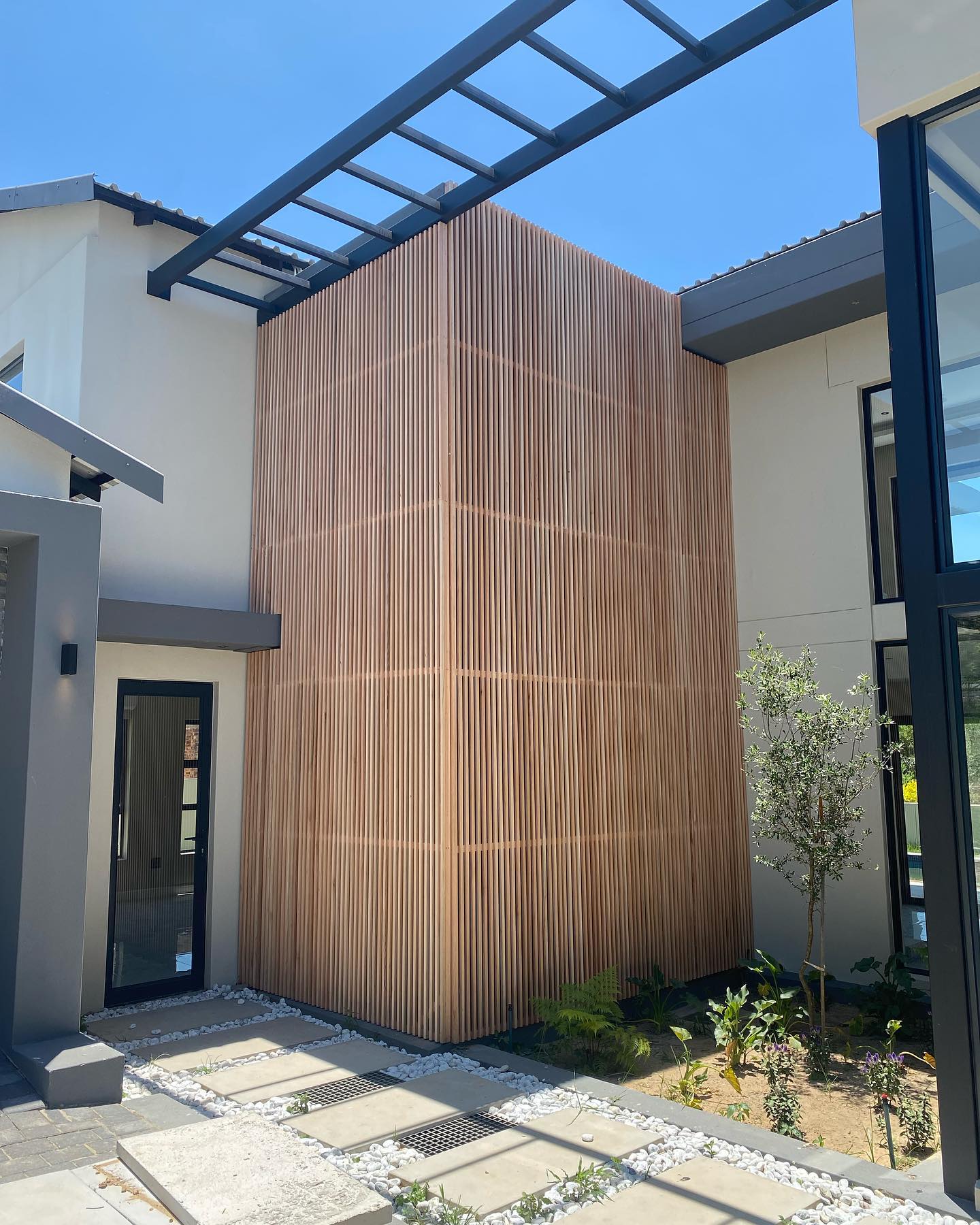 Tall corner timber slat feature wall in an exterior courtyard