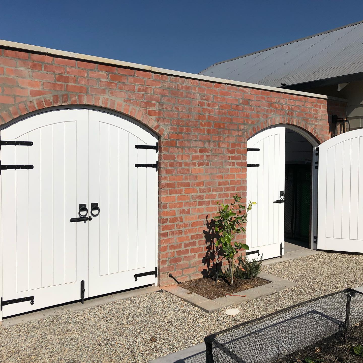 White arched stable-style timber doors set into a brick wall