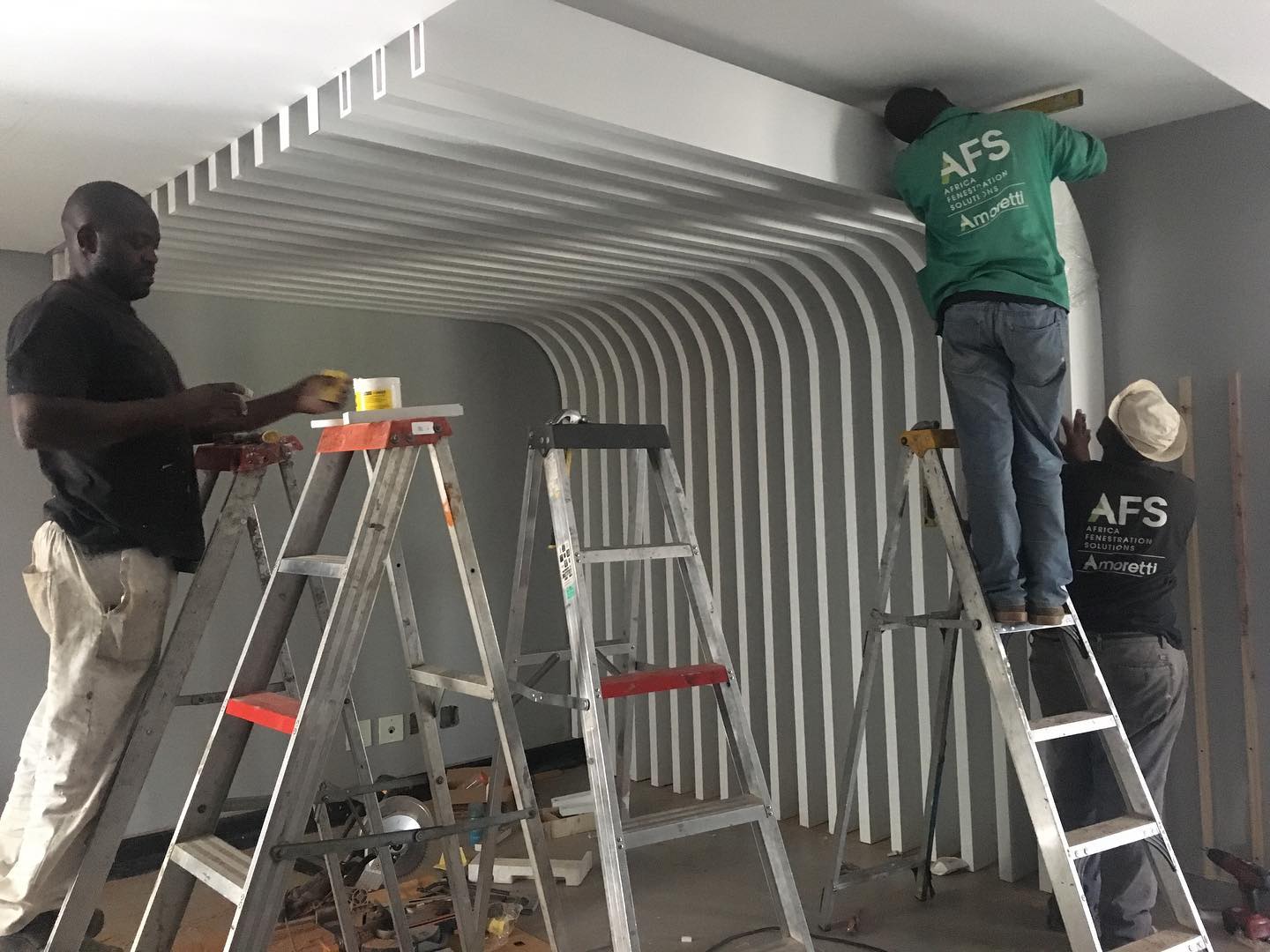 Installers fitting a curved white slat ceiling feature