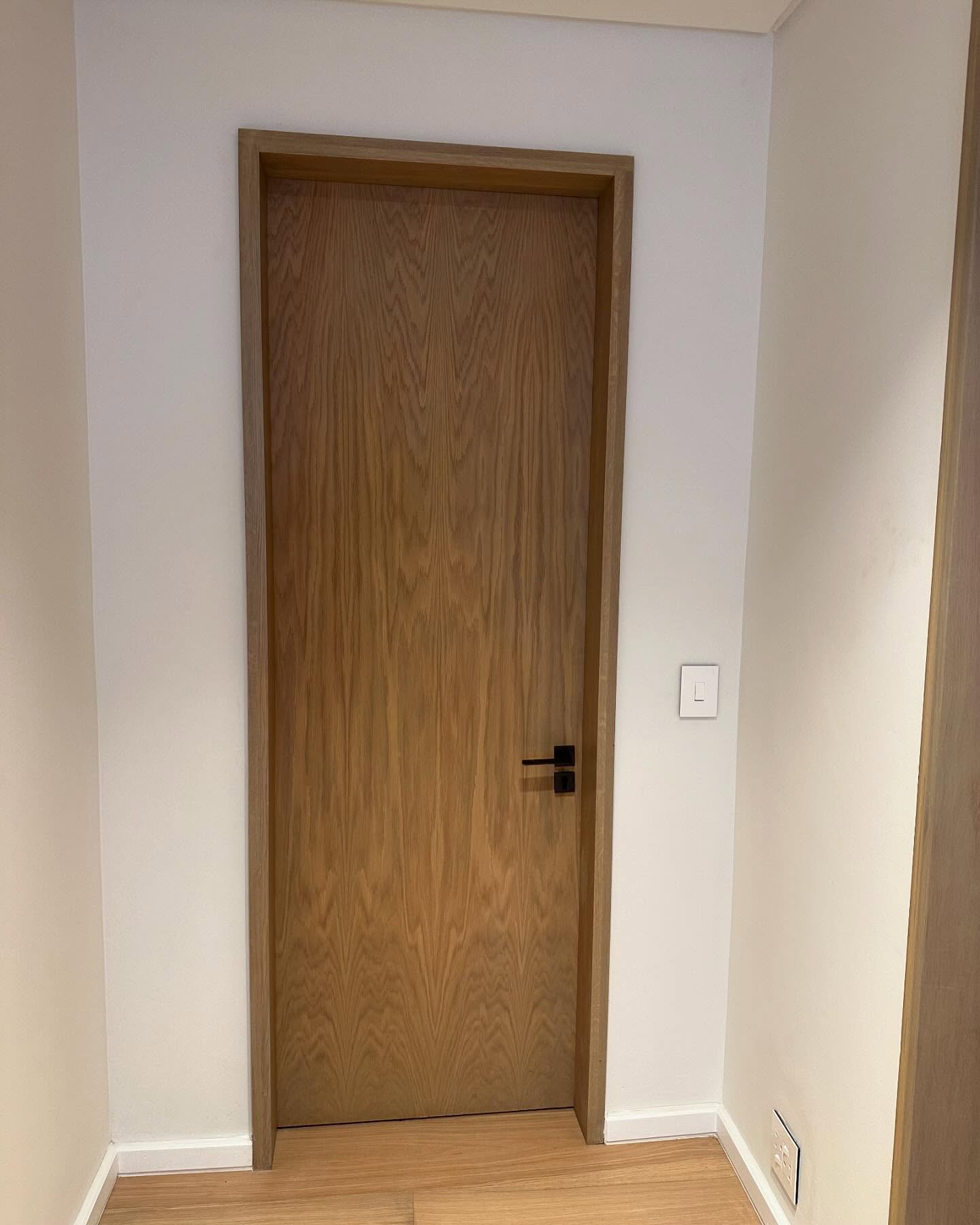 Flush veneer door with figured timber grain and black hardware