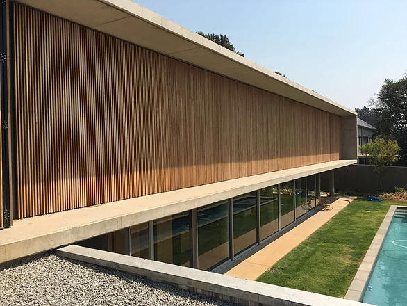 Modern residence with a full-height vertical timber screen facade and concrete roofline