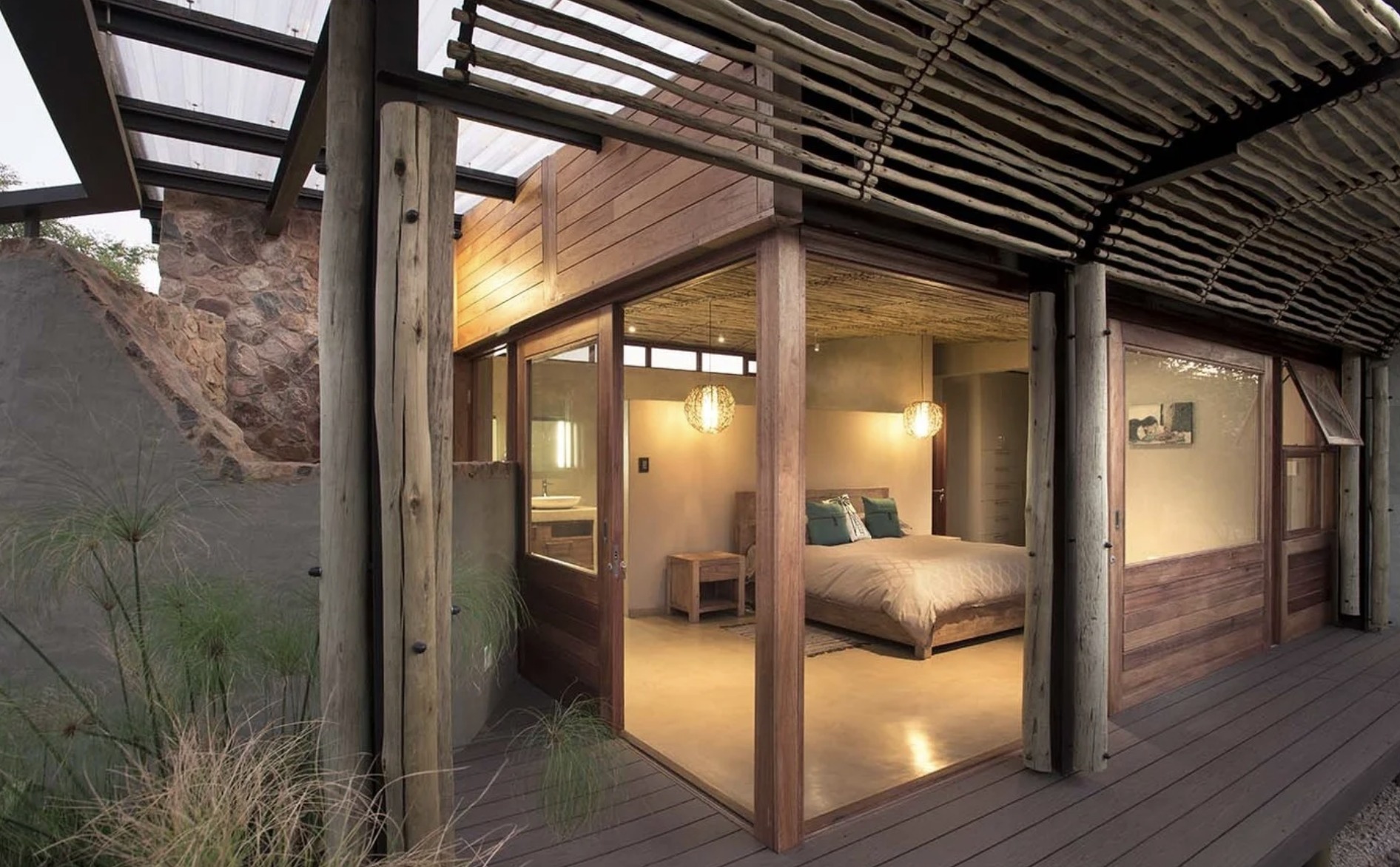Bush Residence bedroom suite opening onto a timber deck beneath a reed-lined pergola