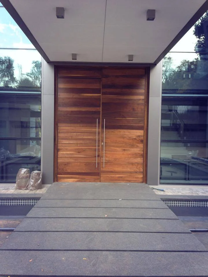 Double pivot horizontal slat Walnut front doors at Irene Residence