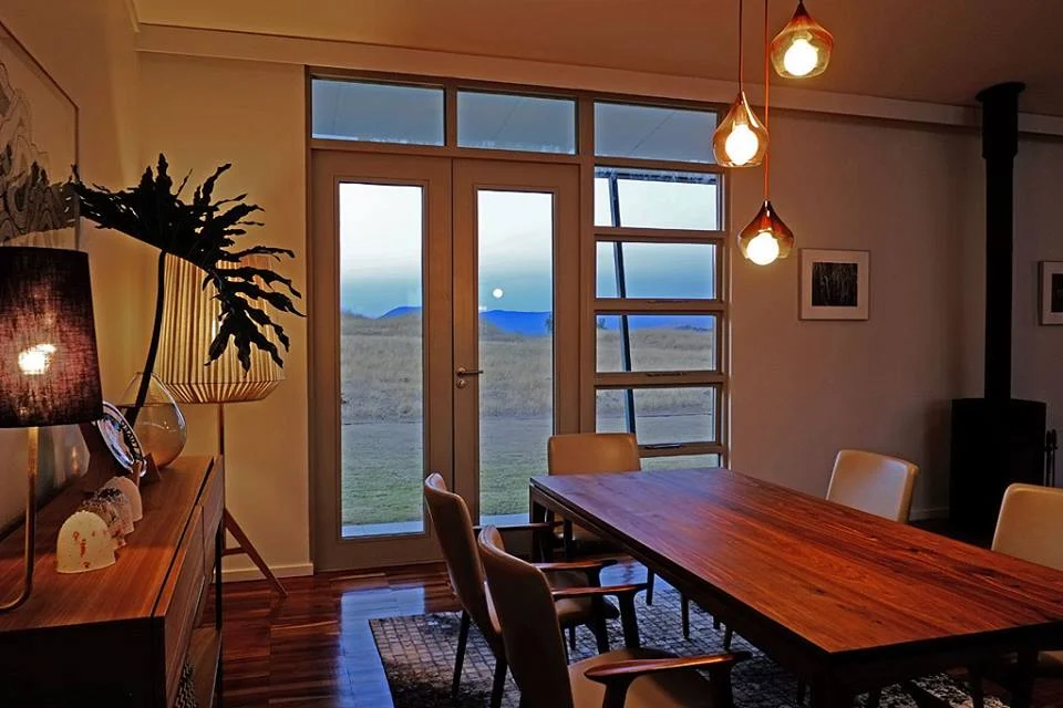 Stand 47 Eco House dining room with timber-framed window and door at dusk