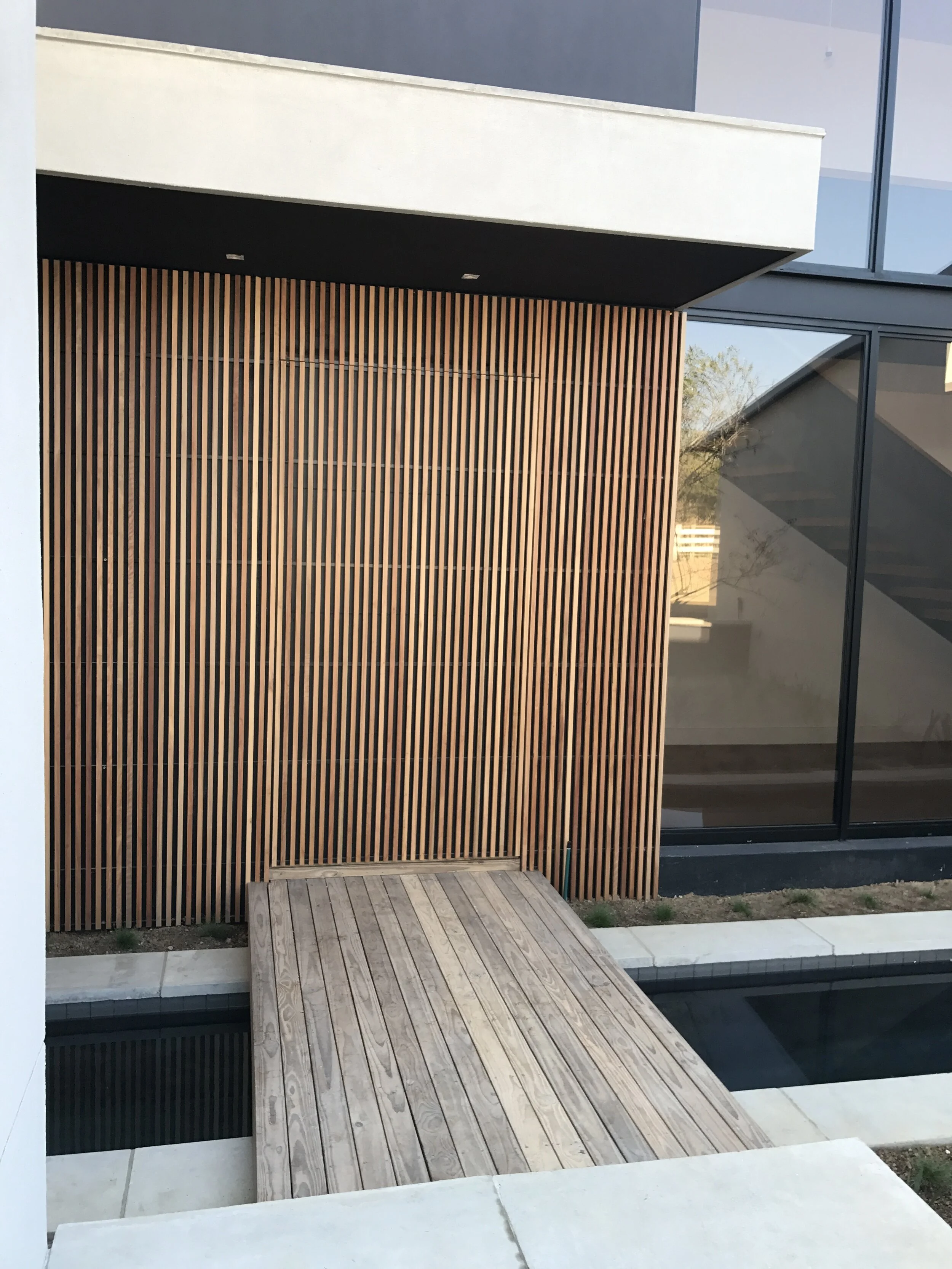 Vertical timber screen with an integrated door beside a pool