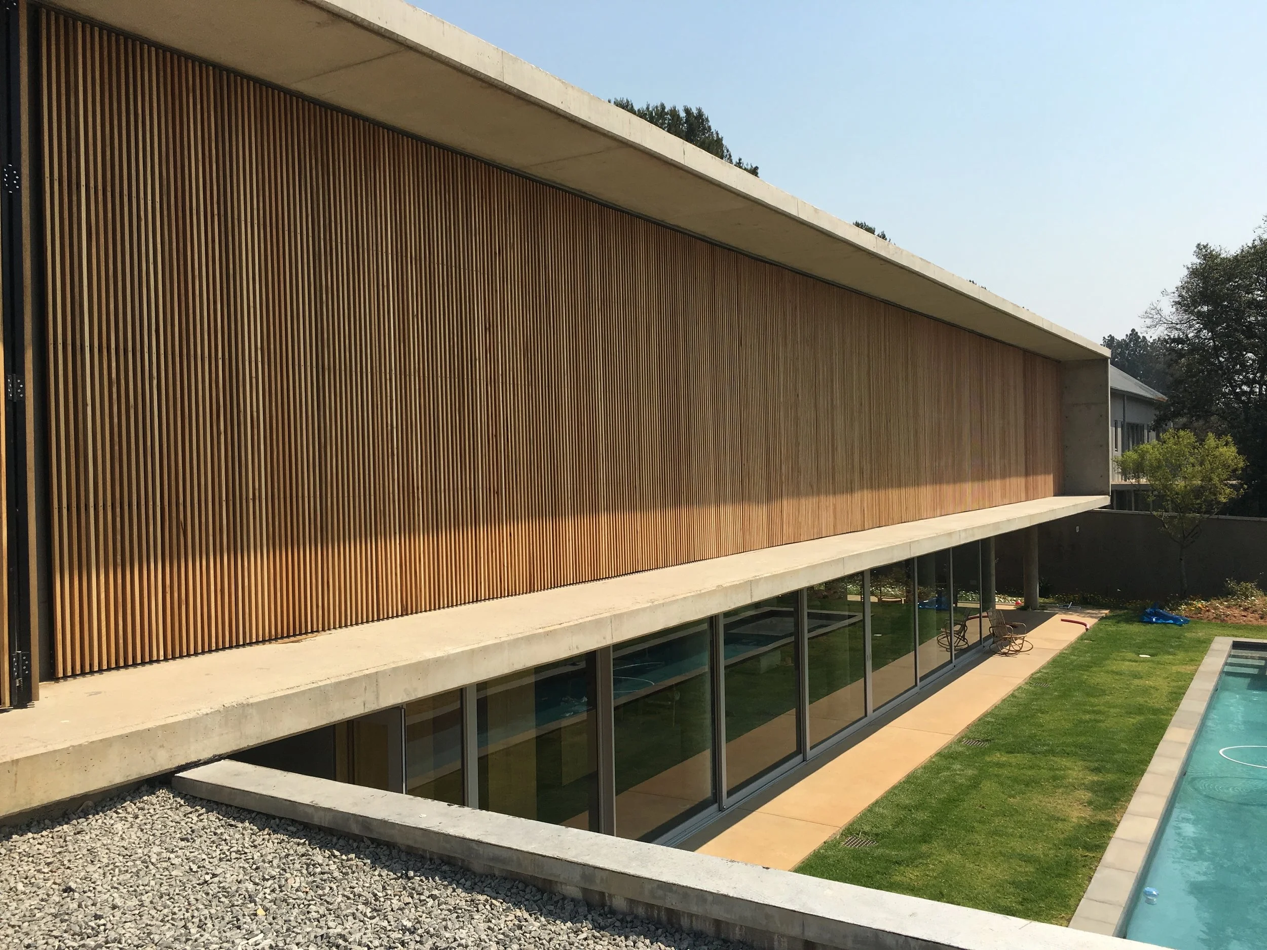Modern residence with a full-height vertical timber screen facade and concrete roofline